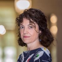 Portrait of Núria Mas, a macroeconomics expert and global economist, seated confidently in a professional setting.
